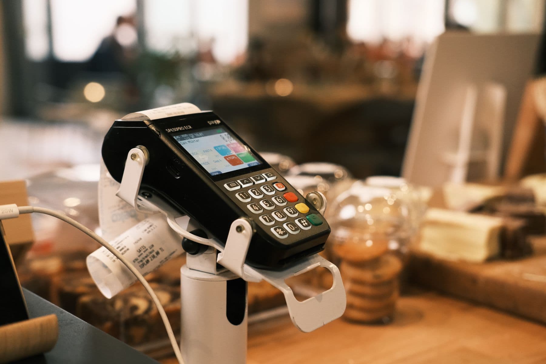 A card reader on a café counter, with pastries and a printed receipt