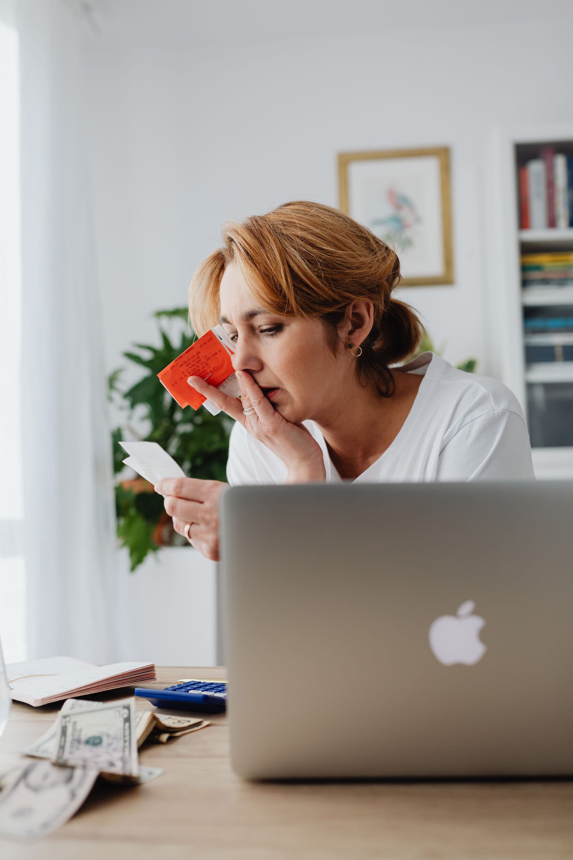 A woman looking through paper receipts at a desk.